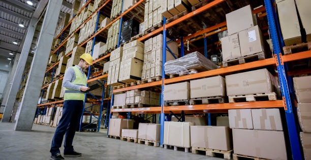 Male worker holding clipboard in warehouse.